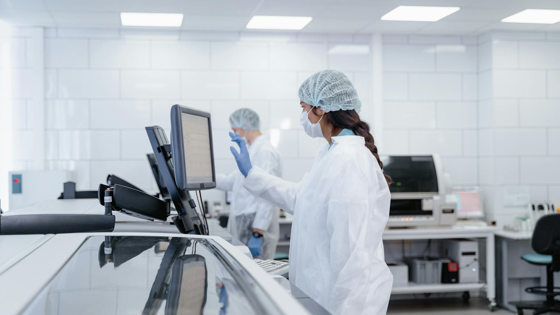 Scientist in protective gear operates equipment in a modern lab.