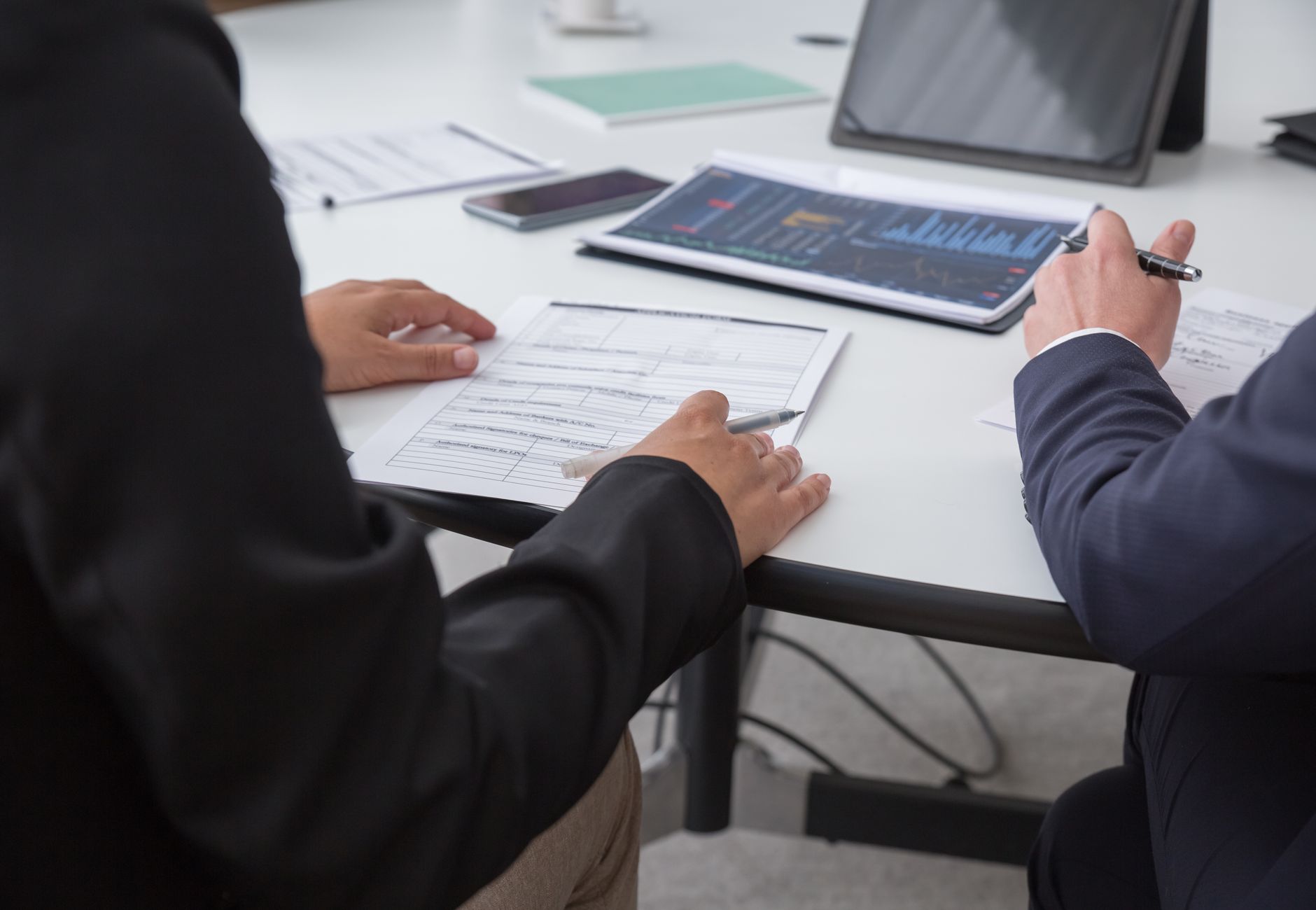 Close-up of professionals reviewing documents in an office setting, focused on analytics.