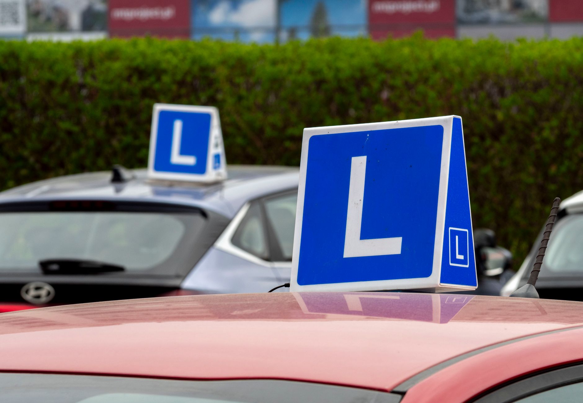 Cars with learning signs parked outdoors in Wrocław, Poland, at a driving school training area.