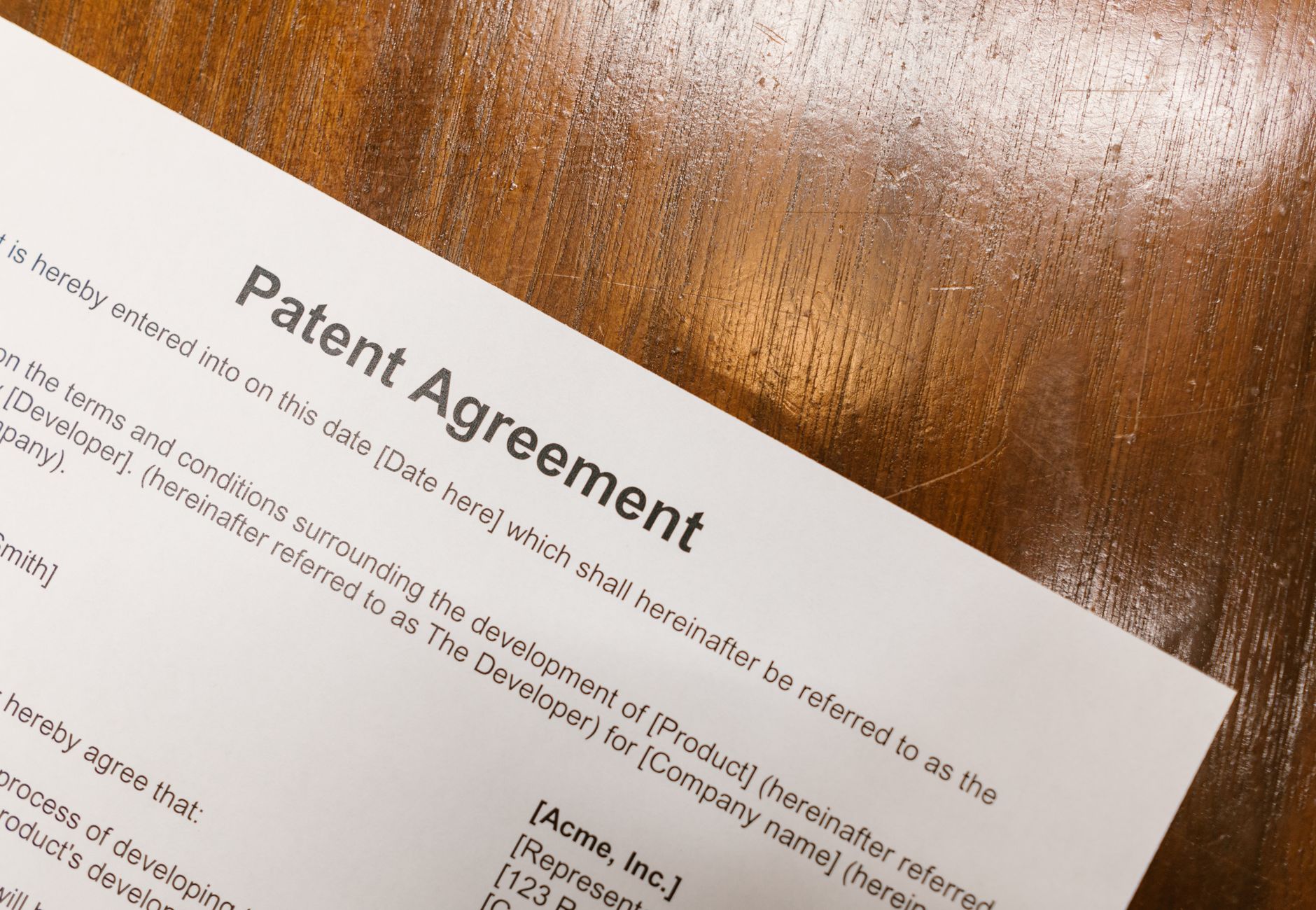 Detailed close-up of a patent agreement document on a polished wooden table.