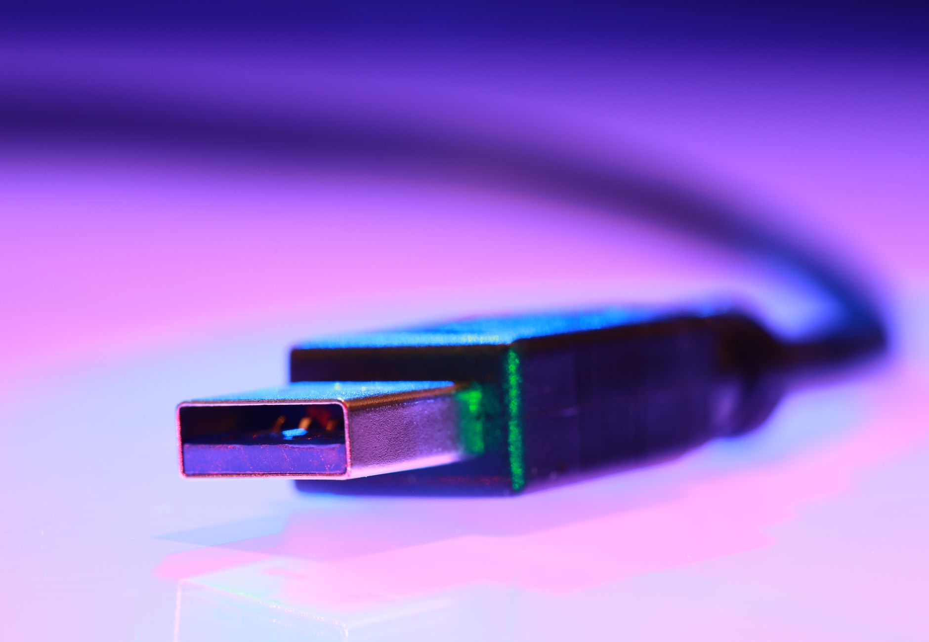 Vibrant close-up of a USB cable against a purple gradient background.